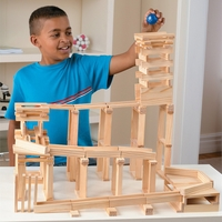 A boy plays with a wooden marble run