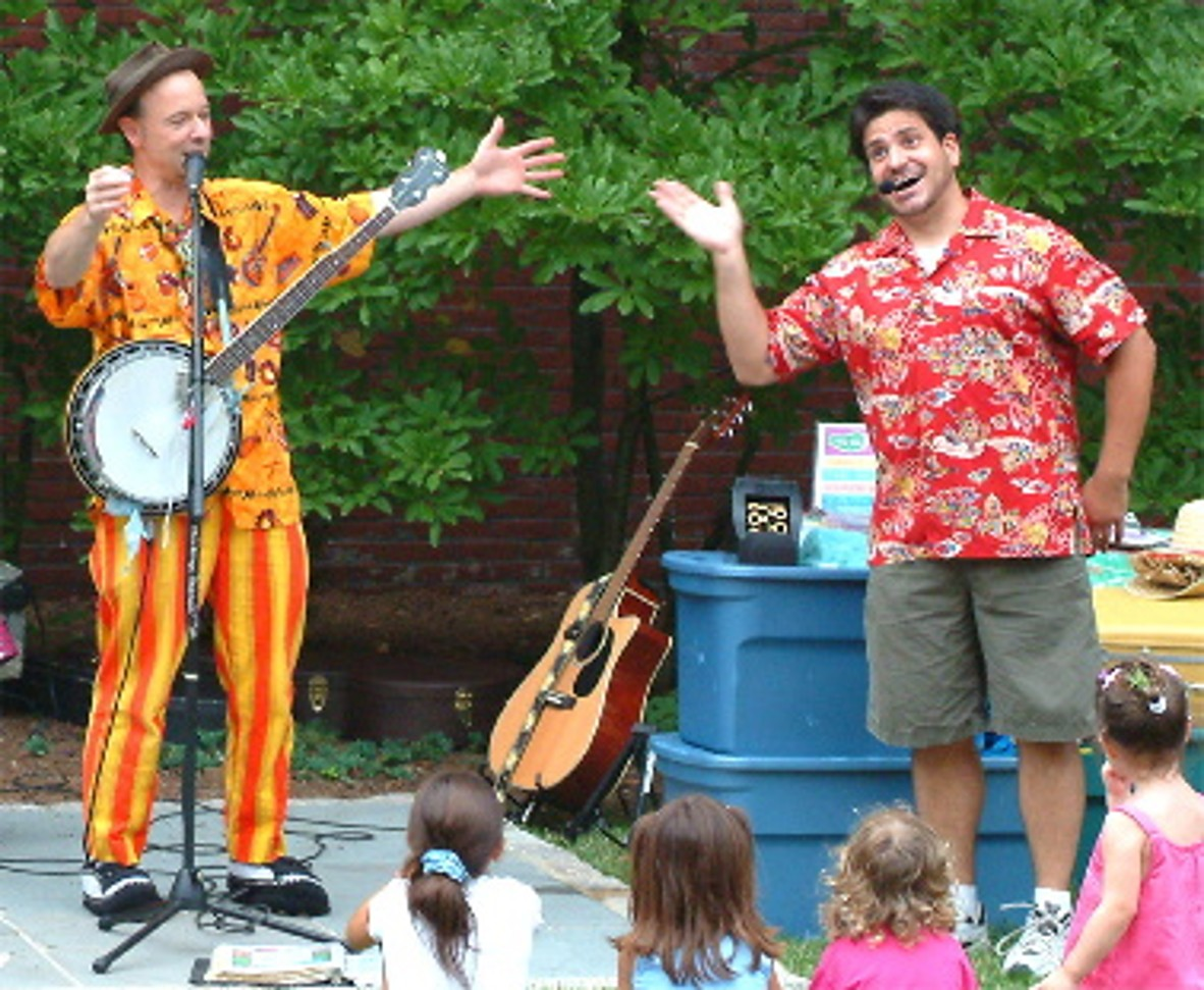 Two men on a stage performing with a banjo