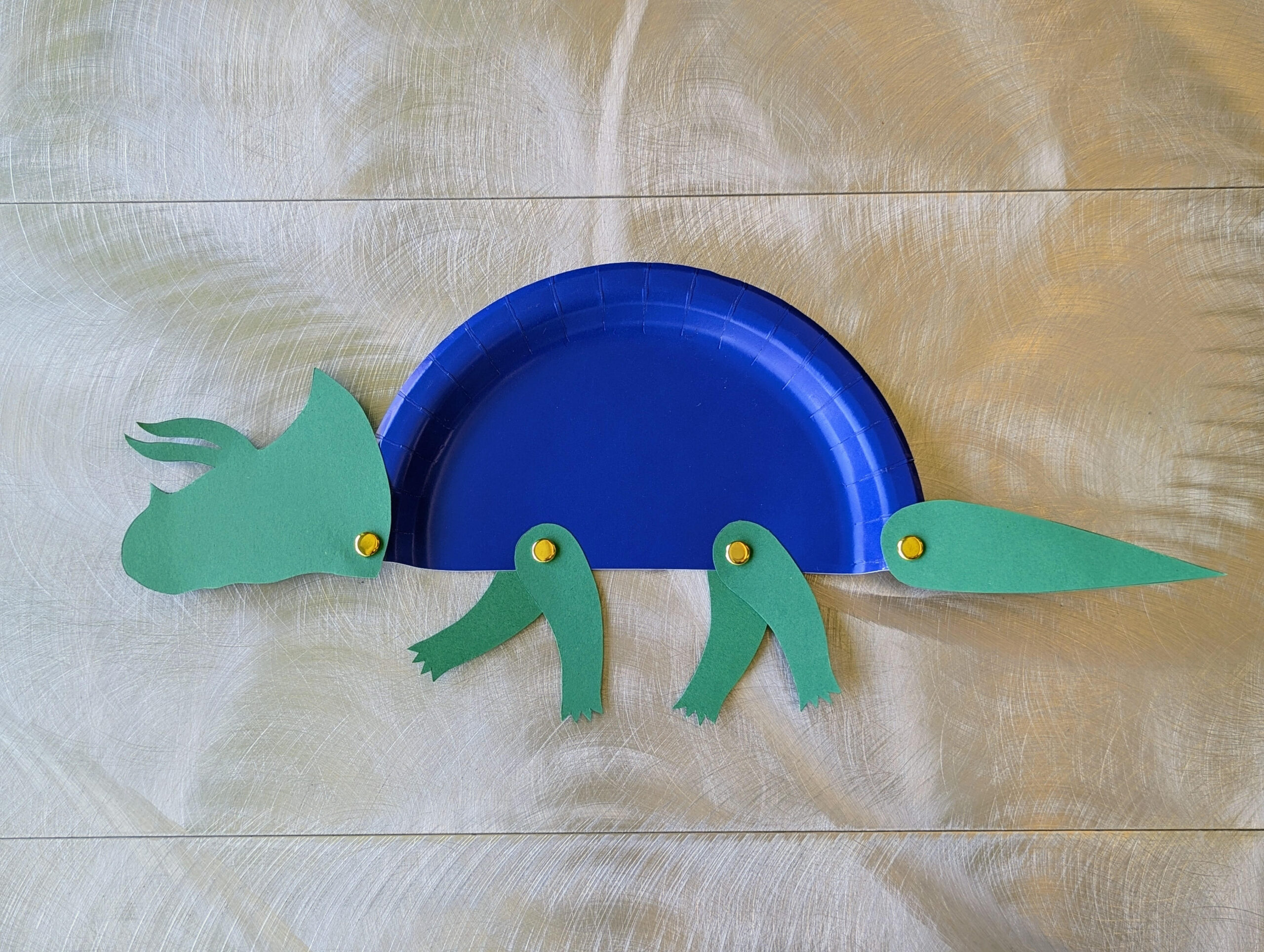 triceratops on a paper plate with brass fasteners